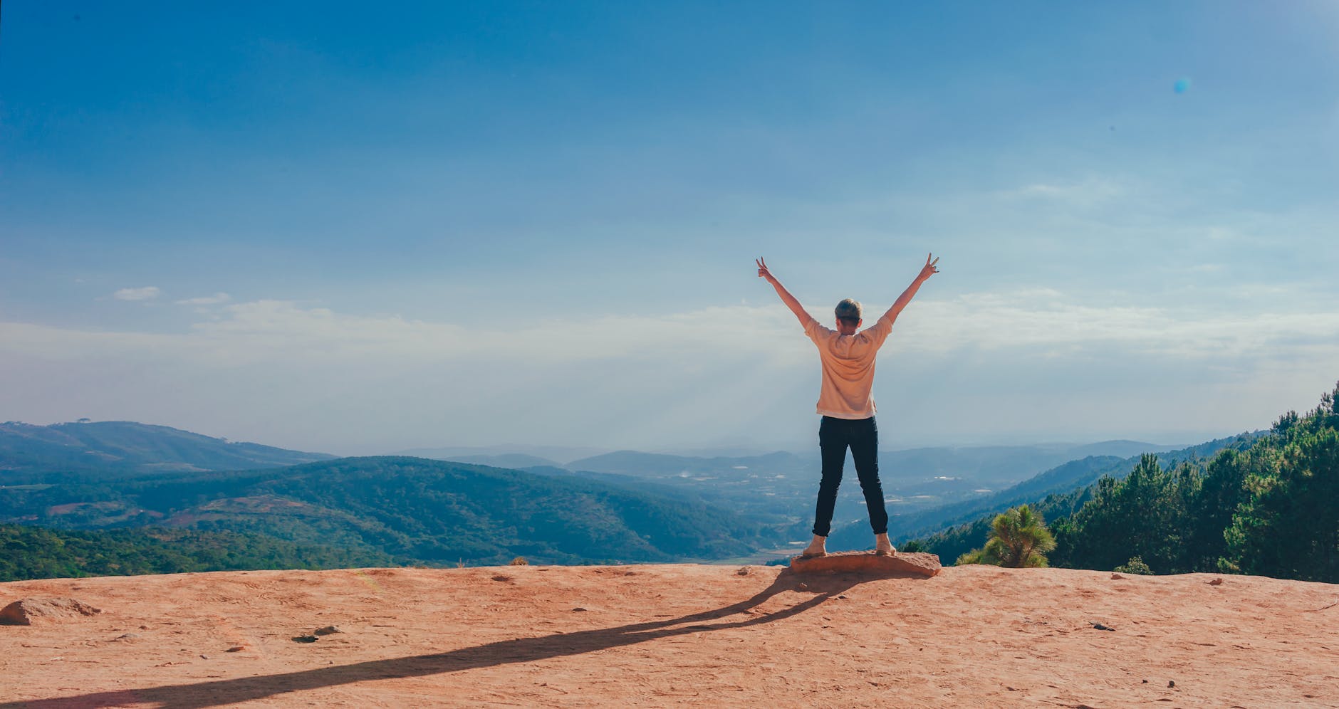 person in beige top on mountain cliff